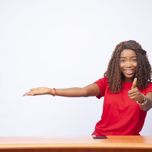 A pretty black female pointing to the space on her side and giving a thumbs up - 
advertising concept